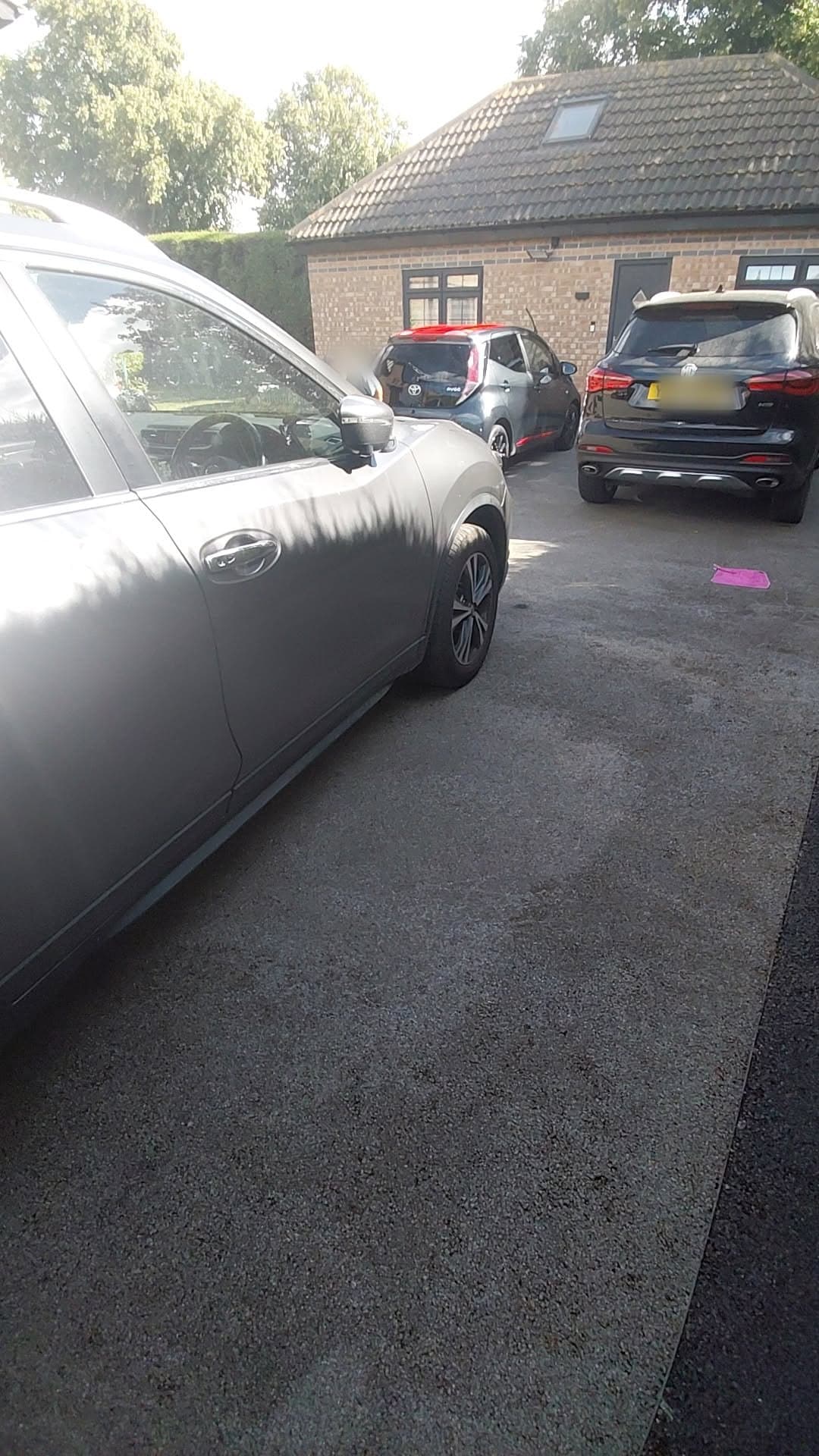 The Nissan X-Trail on a wet driveway, its door and front wheel close up